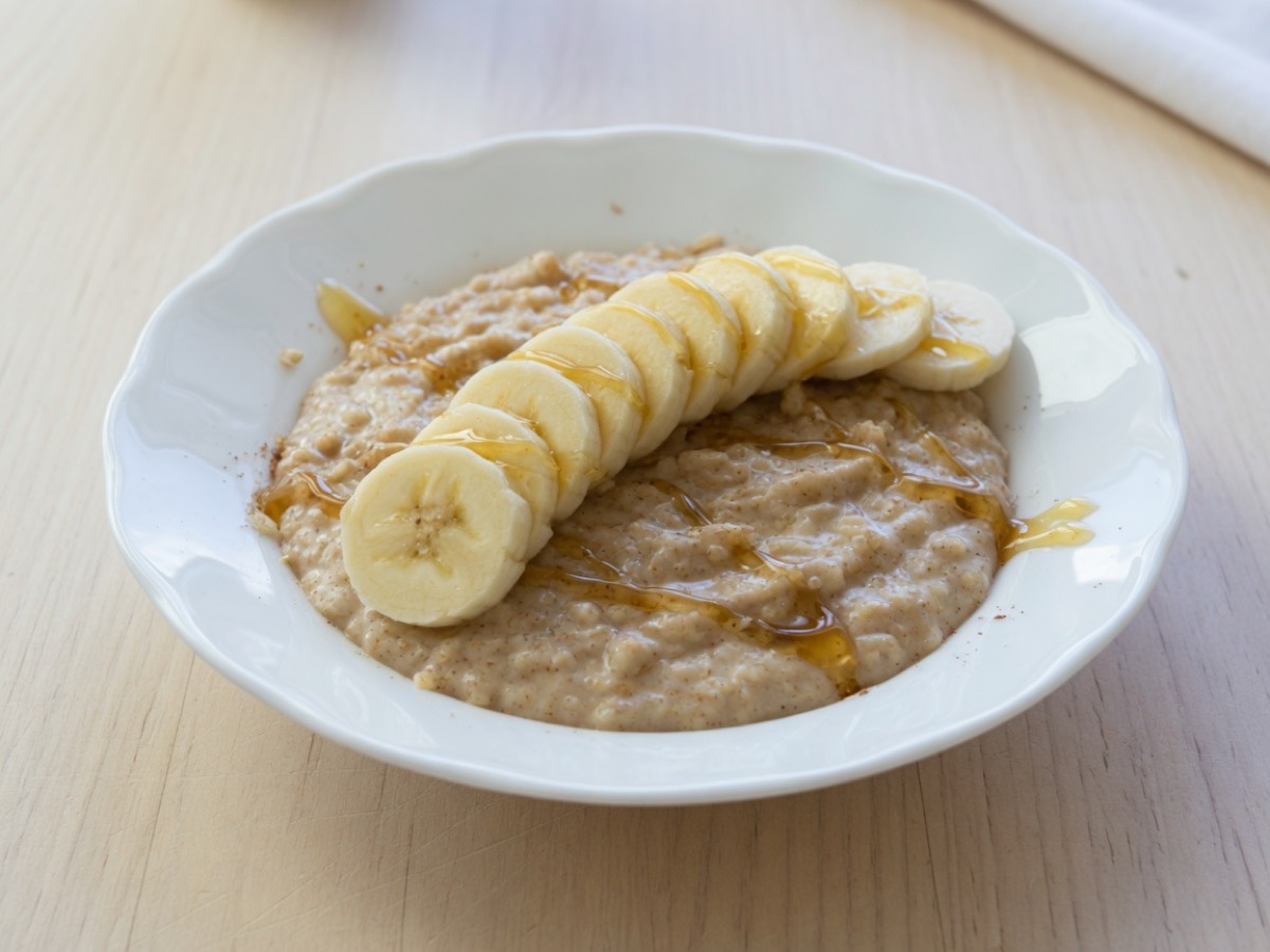 Bowl of cinnamon oatmeal with banana slices and honey
