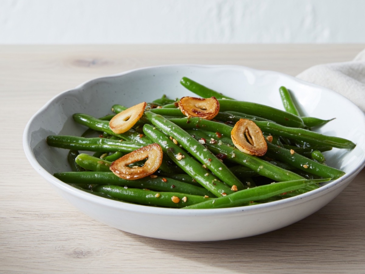 Bowl of green beans topped with browned garlic slices